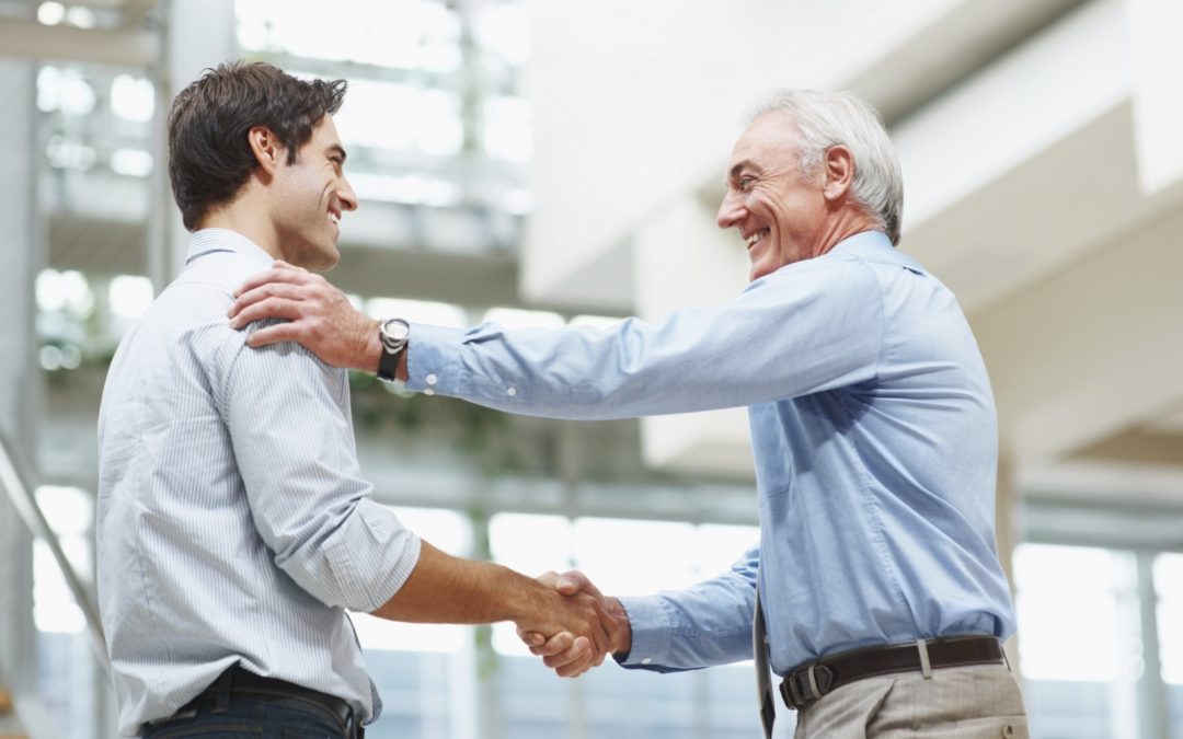 un uomo anziano stringe la mano ad un uomo giovane