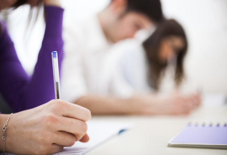 ragazzi chini su un tavolo mantre sostengono un concorso pubblico